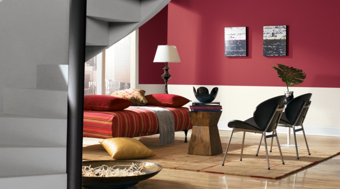 combinacion de colores, sala de estar con paredes en rojo y beige, ventanal sin cortinas, banco rojo con cojines, sillas negras, sulo laminado con tapete