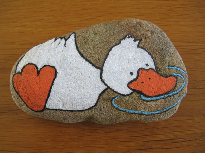 manualidades con piedras, piedra natural grande, dibujo de pato en blanco y naranja y agua con pinatura acrilica