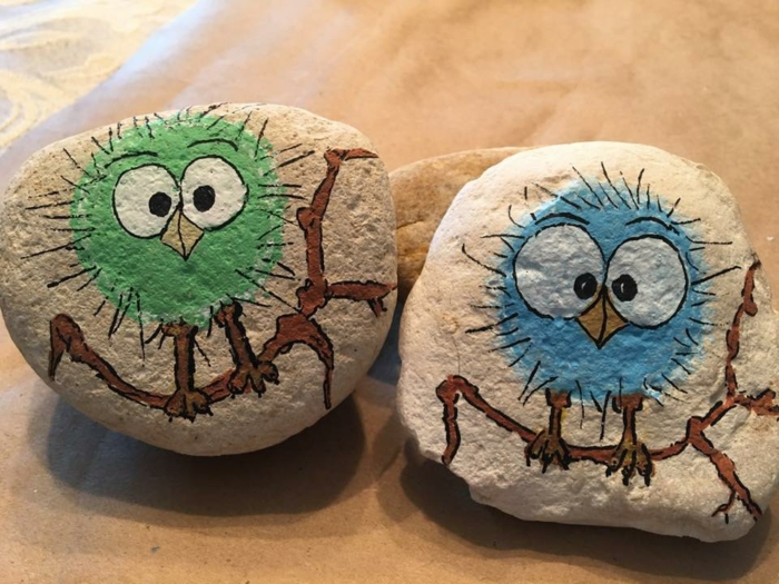 pintar piedras, piedras naturales escarbosos pintadas con pajaritos sobre ramos en verde y azul, manualidades para niños