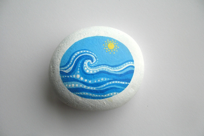 ideas para dibujar, piedra eliptica eliptica cubierta de pintura blanca, paisaje del mar con ondas, sol amarillo, arte sobre piedras