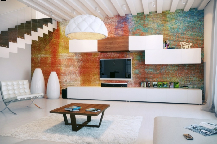 pintura para paredes, salón con techo alto y pared de ladrillo pintada multicolor efecto esponja, televisor, estanterías modernas, mesa de madera, lampara colgande blanca