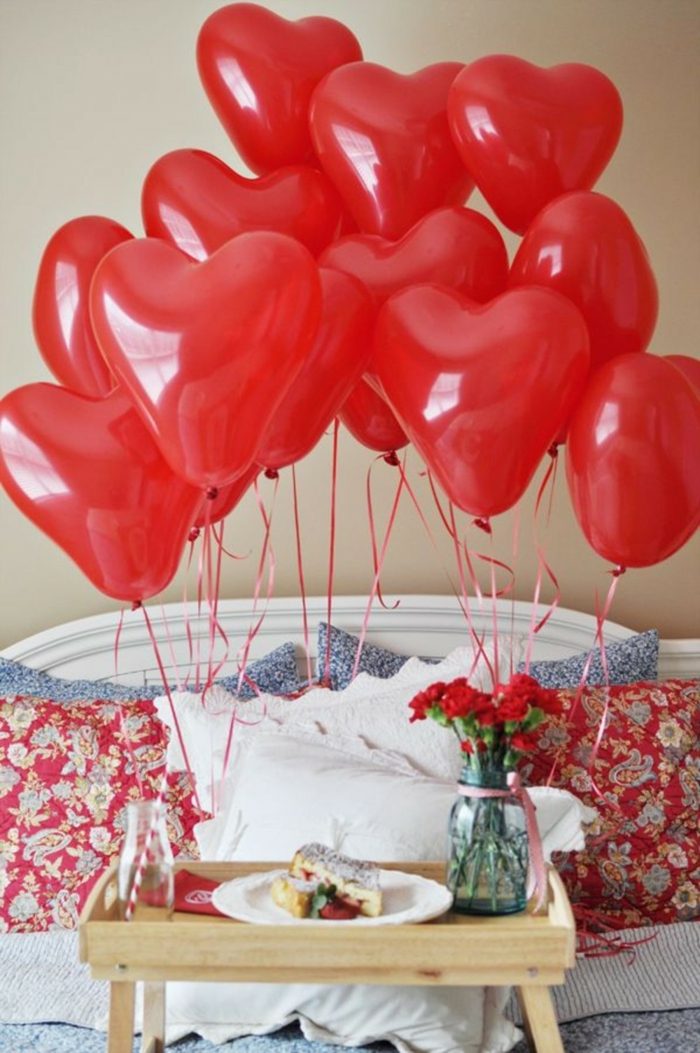 desayuno sorpresa con muchos globos rojos en forma de corazones, tablero de madera con piernas 