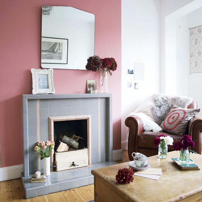 salon pequeño, paredes en rosado y blanco, combinacion de colores, chimenea con baldosas, mesa de madera vintage, espejo grande