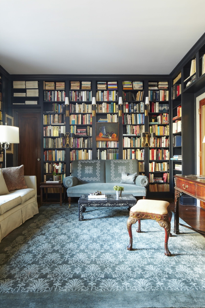 estanterias para libros, idea de decoración clásica, librría de madera gris de suelo a techo, tapete en azul grisáceo, taburete, escritorio vintage