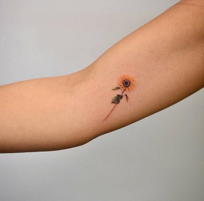 tatuajes de flores, tatuaje pequeño en la parte interna del brazo, girasol de color con tallo, idea minimalista