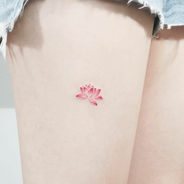 tattoos pequeños, tatuaje de loto minimalista en la cadera de mujer con piel blanca, flor de loto en rosado