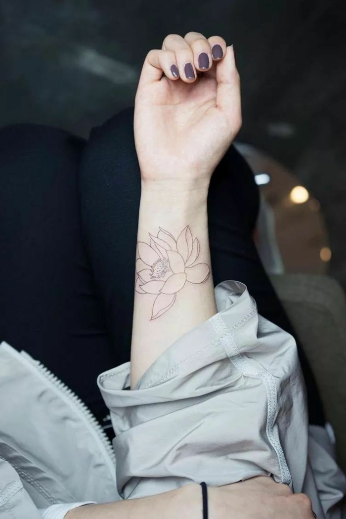 tatuajes de flores, mujer con uñas en morado, tatuaje pequeño en blanco y negro, antebrazo, flor de loto abierta