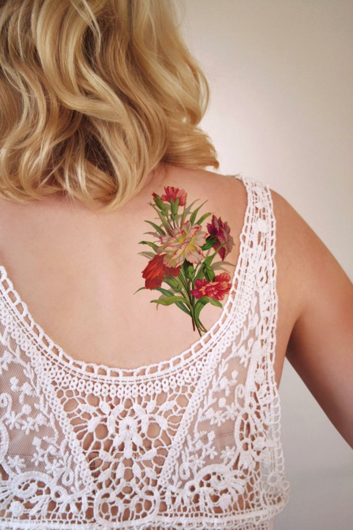 tattoos pequeños, mujer con pelo rubio, tatuaje en la espalda, ramo de claveles realista con hojas verdes