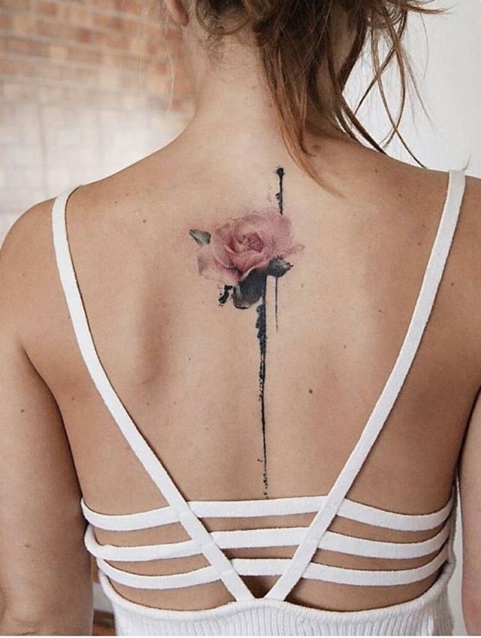 tatuaje espalda, mujer flaca con espalda descubierta, tatuaje delicado con rosa rosada y tallo en la columna vertebral