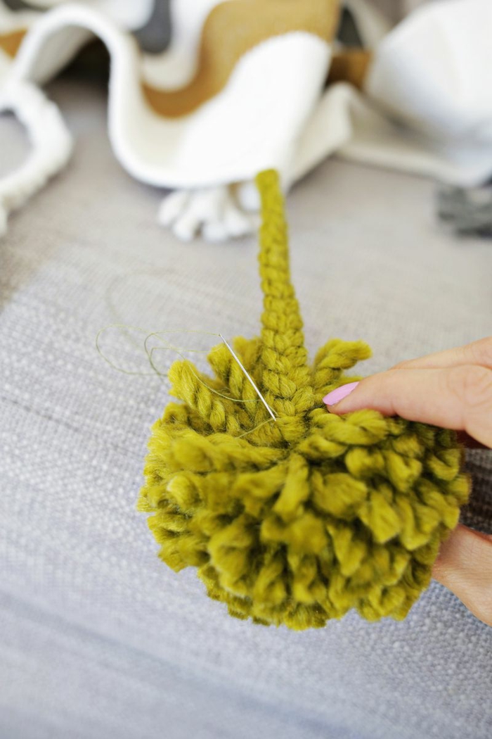 ideas sobre como hacer pompones de lana, pompon grande verde de hilo grueso, como decorar una manta con pompon DIY 
