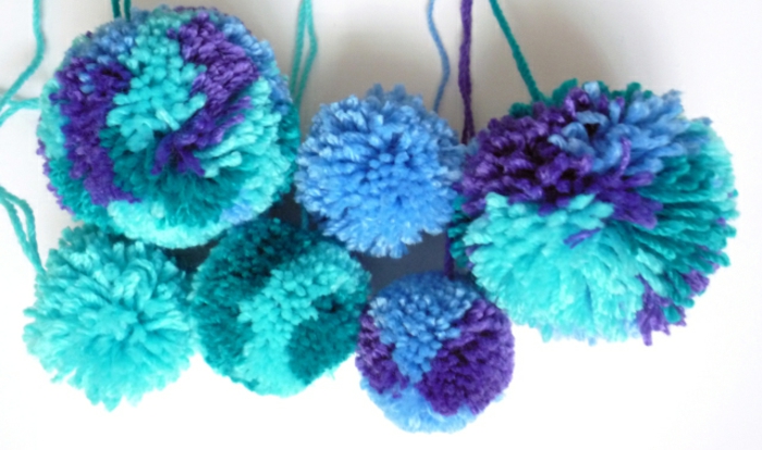 pompones de lana divertidos hechos de hilo en azul, verde y morado, manualdiades con lana fáciles de hacer 