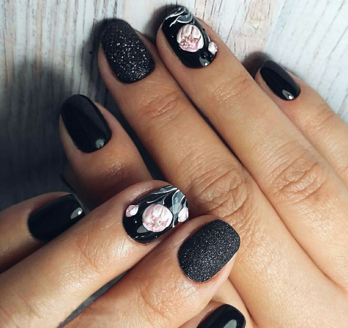ideas de diseños de uñas con motivos florales, flores en rosado en fondo negro, dedo pulgar con gel purpurina acabado mate 