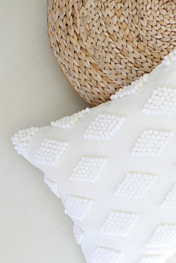cojín blanco decorado con pequeños pompones en blanco, como hacer pompones con lana paso a paso, manualidades útiles 