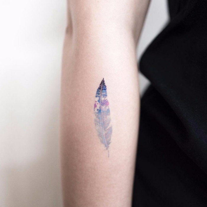 tatuaje delicado para mujer, pluma en colores lilá y rosa acuarela, tattoo antebrazo, tatuajes minimalistas