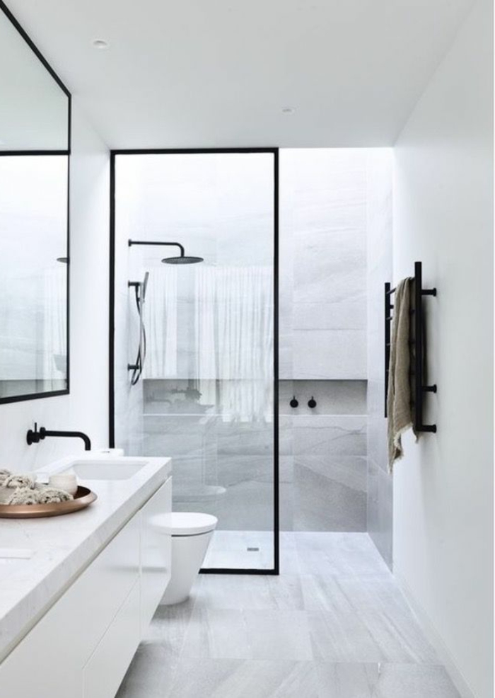 cuarto de baño largo y estrecho, decoracion baños pequeños, marmol, lavabo doble, mampara de vidrio, toallero negro, pared con nicho