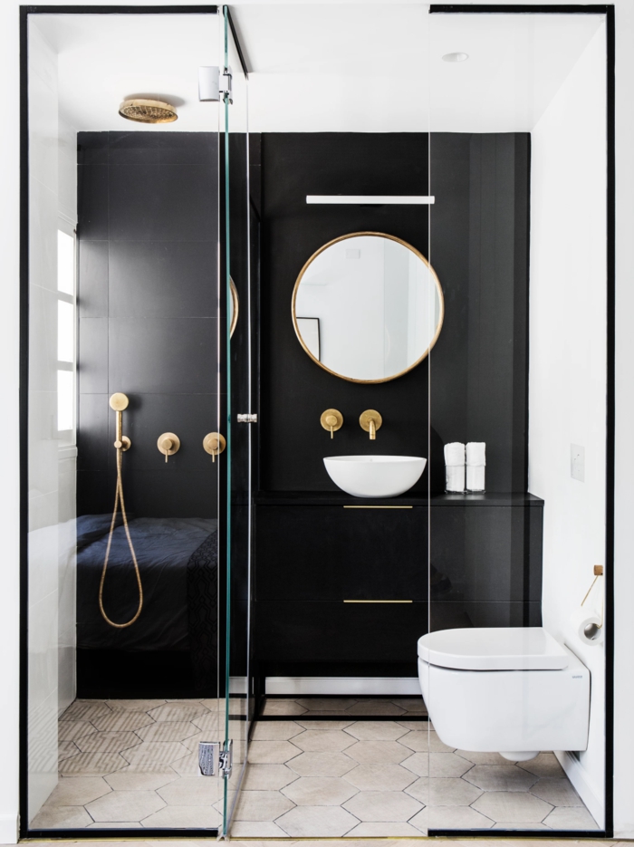 cuartos de baño pequeños, decoración moderna con pared de acento en negro, espejo redondo, mini lavabo, metal color dorado