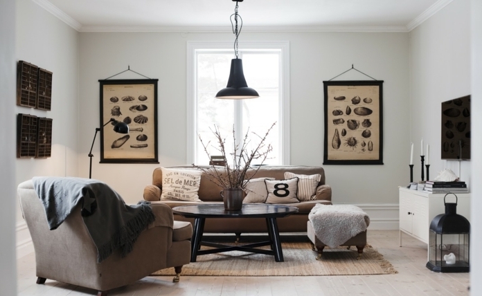 decoracion estilo nordico, sala de estar en marrón y negro, paredes decoradas con fotos de especies biológicas, lámpara colgante, mesa negra redonda de madera, sillón con patas, portavelas y televisor