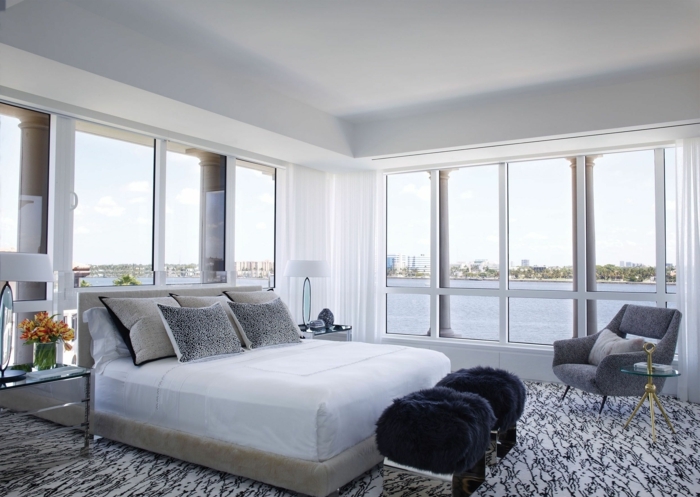 dormitorio con vista al rio, ventanales, cama doble, taburetes negras, moqueta en blanco y negro, tonos grises, sillon y mesilla de vidrio, habitacion gris