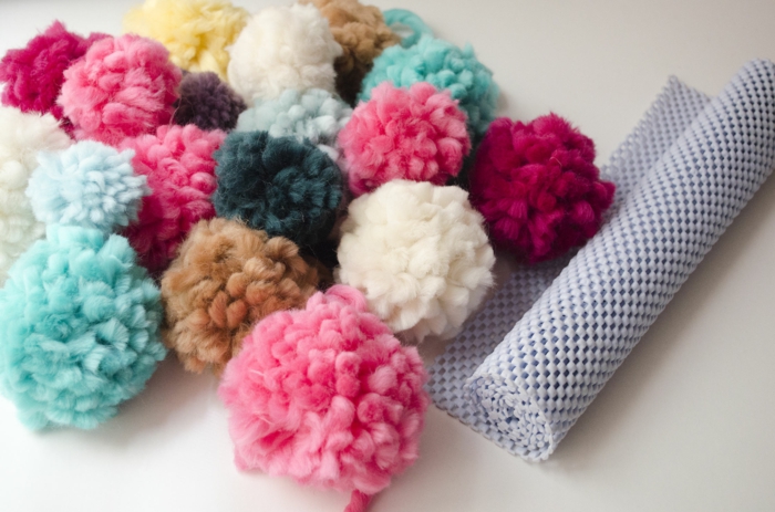 ejemplo de una alfombra de pompones hecha a mano, preciosos pompones DIY en diferentes colores y estera con agujeros 
