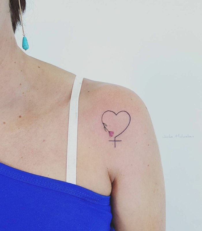 tatuajes con significado, combinacion de tres simbolos, corazon, cruz y amapola, tatuaje hombro mujer, blusa azul, correa blanca