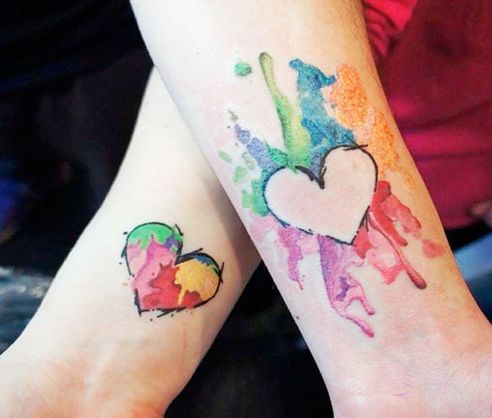 tatuajes de hermanas, tatuajes originales de color en la muñeca, corazón en explosión de colores estilo acuarela, tatuajes parecidas pero no iguales