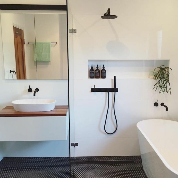 baño pequeño con ducha y bañera, decoración nordica en blanco y negro, lavabo con encimera de madera, pared con nicho, baños pequeños con ducha