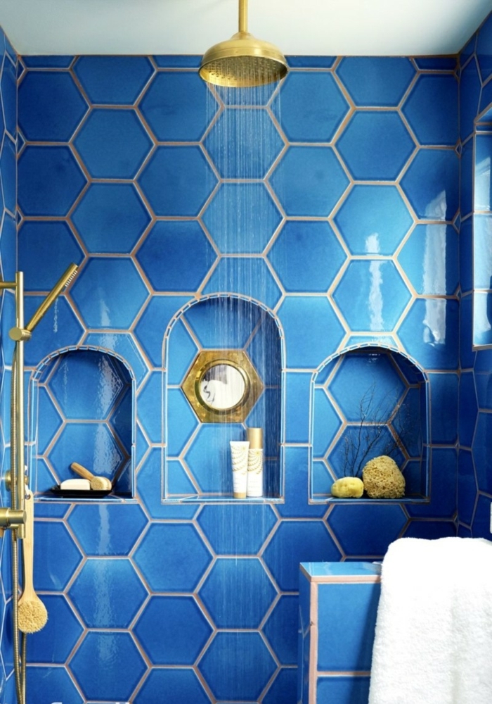 decoración original de baños en azul royal con baldosas hexagonales, nichos en la pared, ducha con efecto de lluvia, metal color dorado, baños modernos