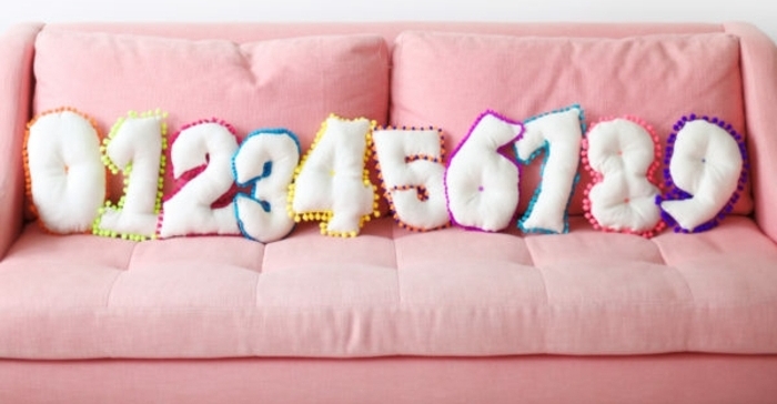 precioso sofá en capitoné color rosa decorado de cojines decorativos DIY en forma de los números de cero a nueve, manualidades con fieltro para regalar