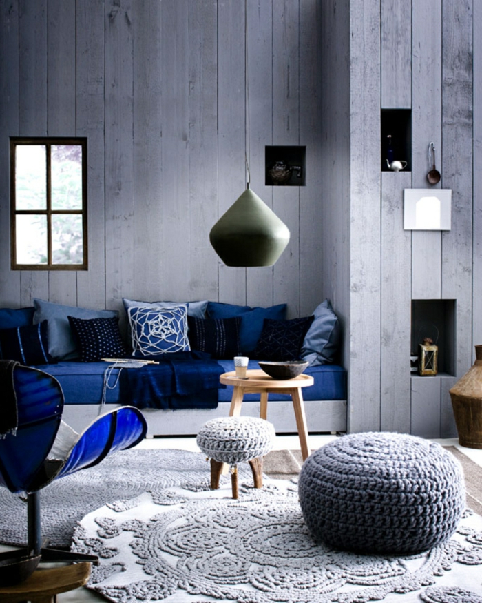 combinación de estilo rústico y escandinavo, salón en azul, paredes de listones con nichos decorativos, decoracion nordica, ventana pequeña, tapete de ganchillo, mini mesa redonda de madera