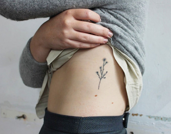 mujer delgada con lunares ty tatuaje en el torso, flor cardo pequeño, ltatuajes chicos, diseños de flores