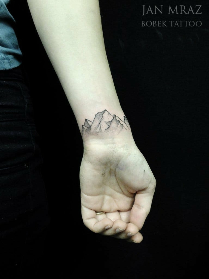 tatuaje moderno con efecto 3D, muñeca parte interior, cadena montañosa, mano mujer con anillo, tatuajes pequeños para mujeres originales