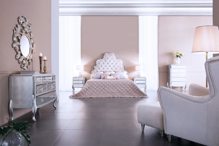 precioso dormitorio decorado en estilo vintage, paredes en color rosa y espejos decorativos ornamentados, cama con cabecero en capitoné