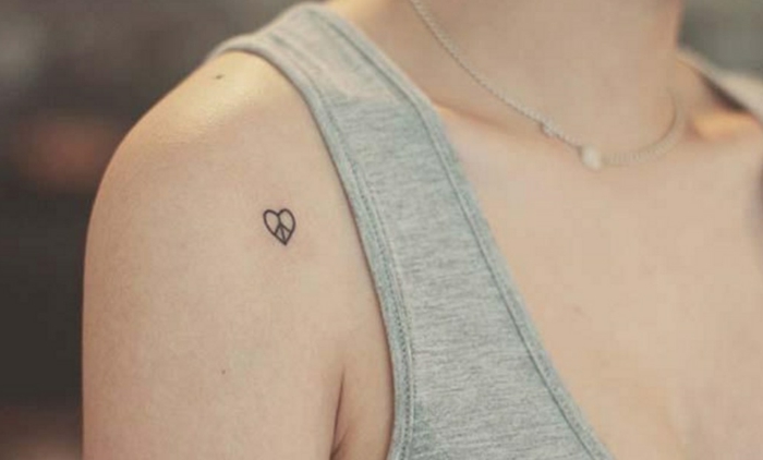 tatuajes elegantes, diseños para mujeres, tatuaje hombro, simbolo de paz en corazon pequeño, mujer con blusa gris y collar
