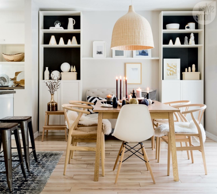 muebles estilo nordico, salon comedor pequeño, sofá beige en capitoné, estanterías paralelas, mesa con velas, sillas de madera, suelo laminado, lámpara colgante grande
