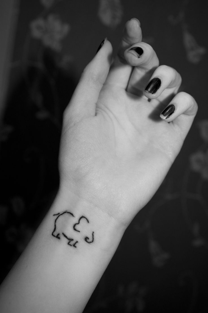 idea de tatuaje con elefante estilizado en la parte interior de la muñeca, mano de mujer con esmalte de uñas, foto en blanco y negro, tatuajes flechas