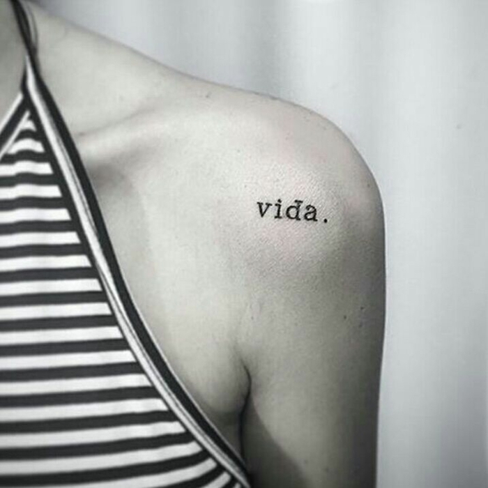 mujer delgada, tatuaje en el hombro, tatuajes con significado. palabra en fondo máquina de escribir, blusa con escote halter