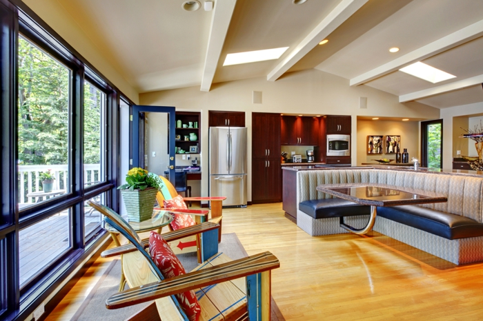 salon con techo inclinado, salon cocina en estilo moderno con tonos claros y cálidos, sofá tapizada de piel 