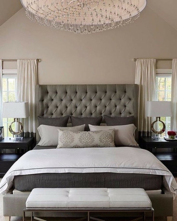dormitorio lujoso, decoracion habitacion matrimonio, cabecero tapizado en capitoné, lámpara de araña, ventanas paralelas, pie de cama