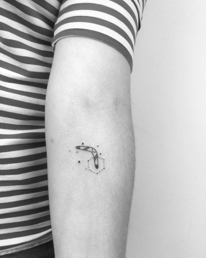 foto en blanco y negro, tatuajes con significado, antebrazo hombre, diseño con boomerang, camiseta rayada