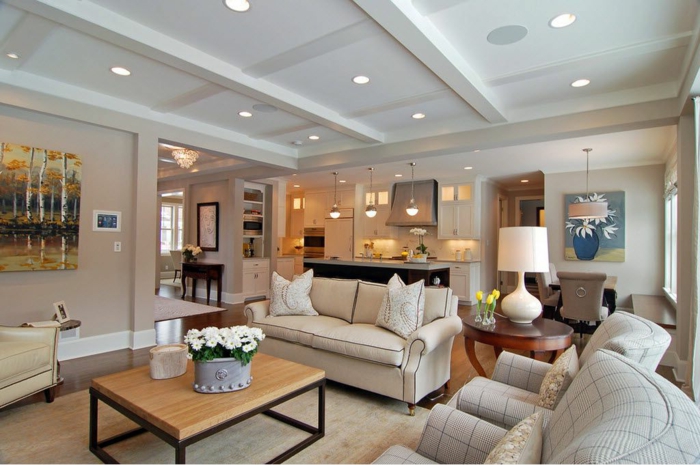 interior en blanco con salon cocina, sofás y sillones cómodos en beige con estampados en cuadrados, mesa de madera baja