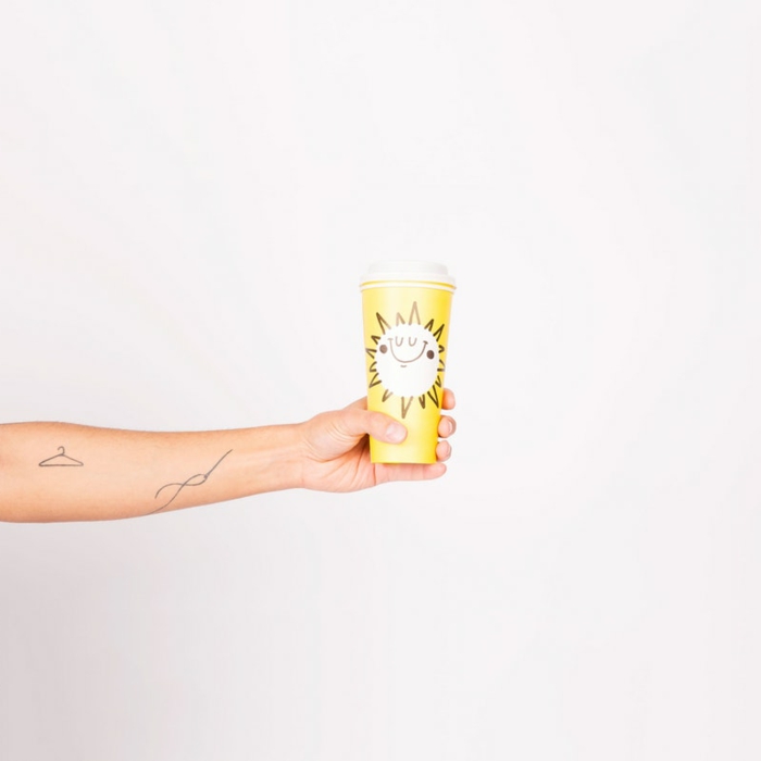 tatuajes minimalistas, mano colgando taza de cafe amarilla con sol, antebrazo tatuado con percha y aguja con hilo
