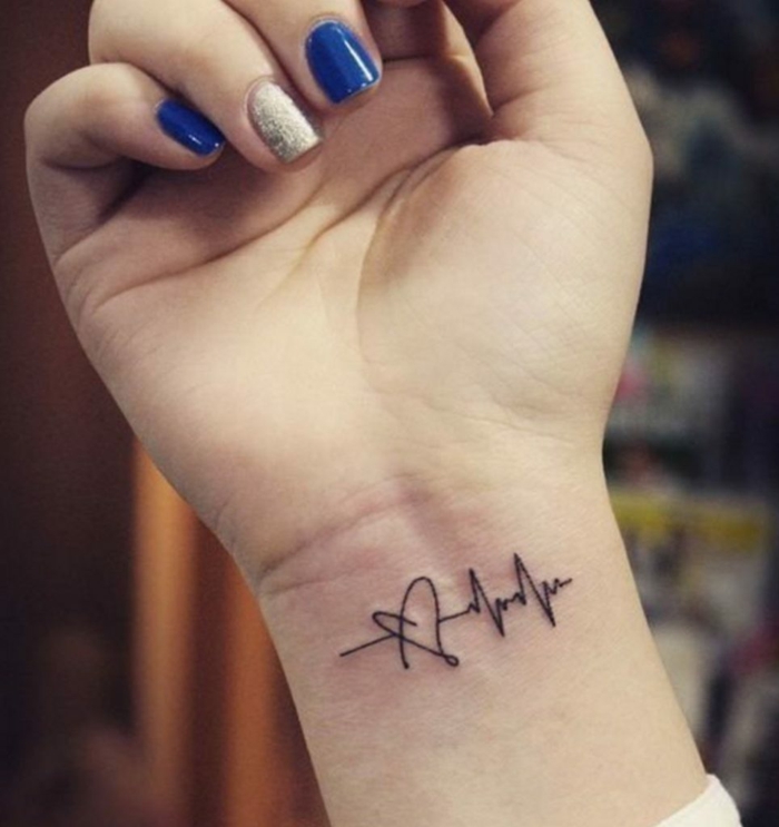 tatuaje con significado, mano de mujer con uñas pintadas, tatuaje negro en la muñeca, frecuancia cardíaca y corazón, tattoo en la muñeca