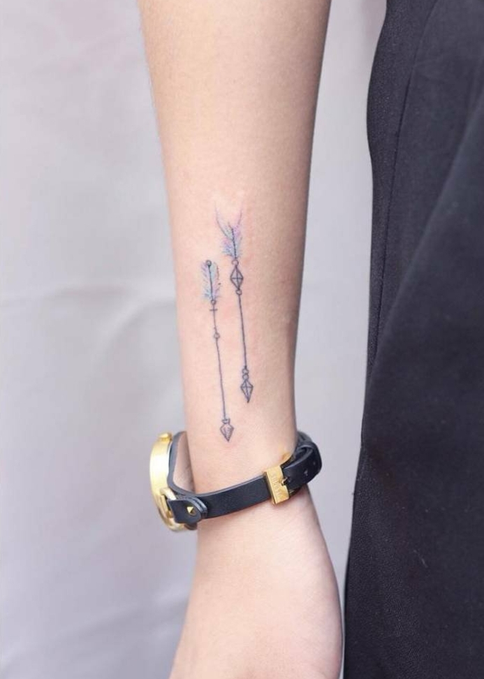 tatuajes flechas, diseño delicado para mujeres, flechas negras con color azul y morado, mano de mujer con reloj con correa negra