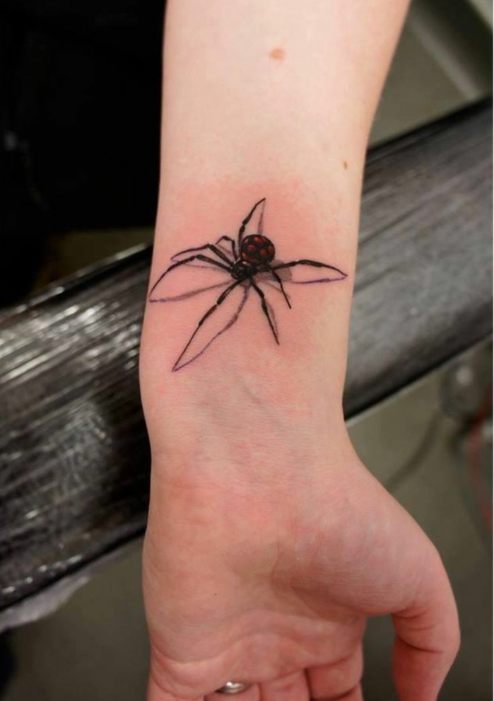 mujer con anillo en el dedo anular, tatuaje de una araña en la muñeca con efecto 3D, tatuajes flechas