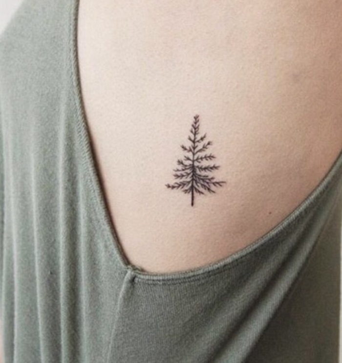tatuajes pequeños mujer, mini tattoo con pino en negro, tatuaje en el torso bajo el brazo, blusa color kaki
