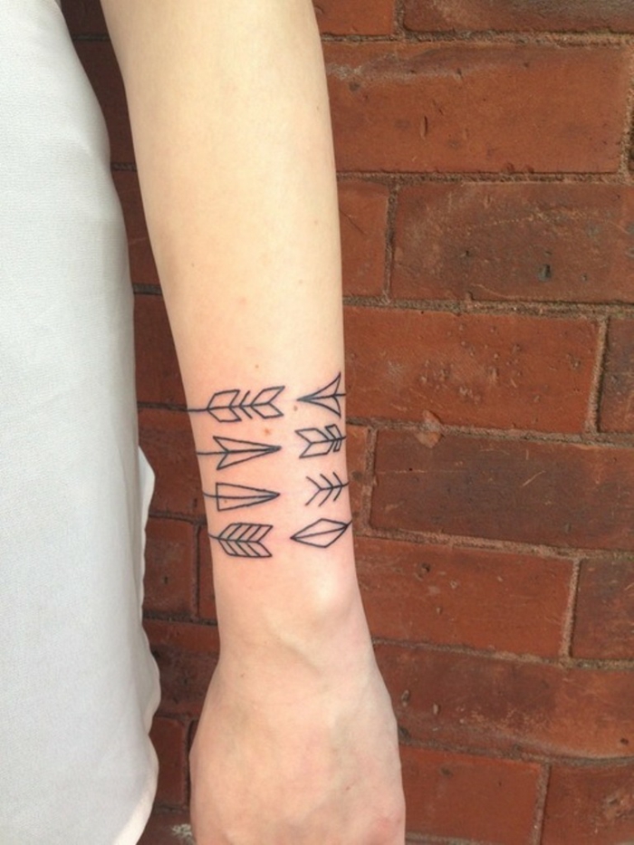 diseño geométrico, tatuaje tipo brazalete con tres flechas en la muñeca, brazo de mujer, tatuajes de nombres en la muñeca