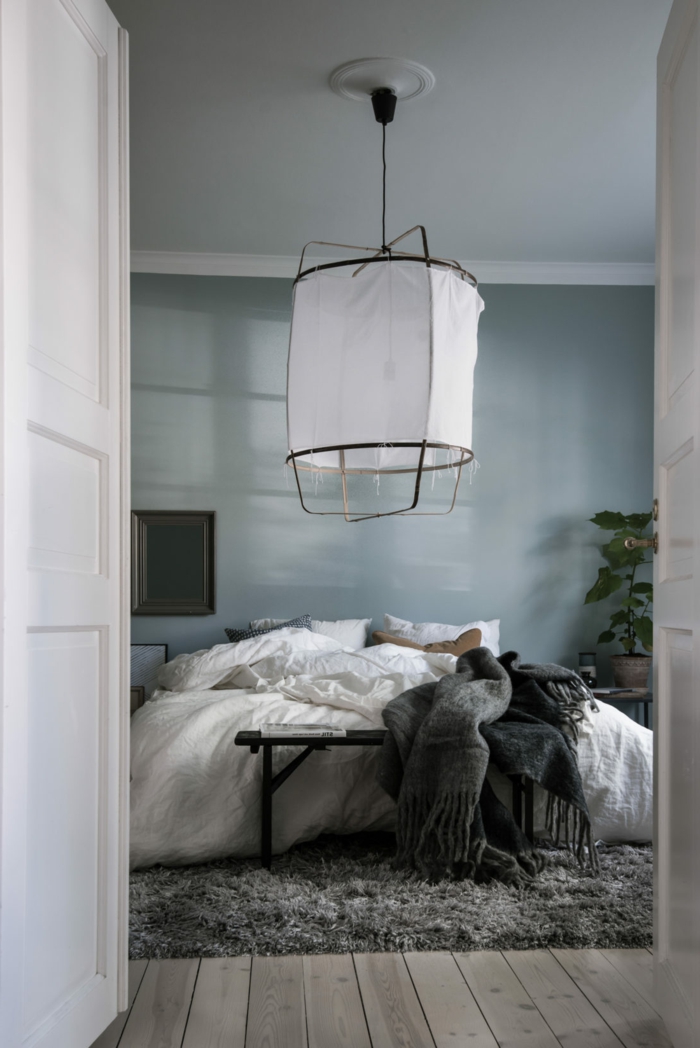 dormitorio minimalista, habitacion gris y blanca, pared en gris azulado, lampara grande colgante, suelo de tarima, tapete peludo