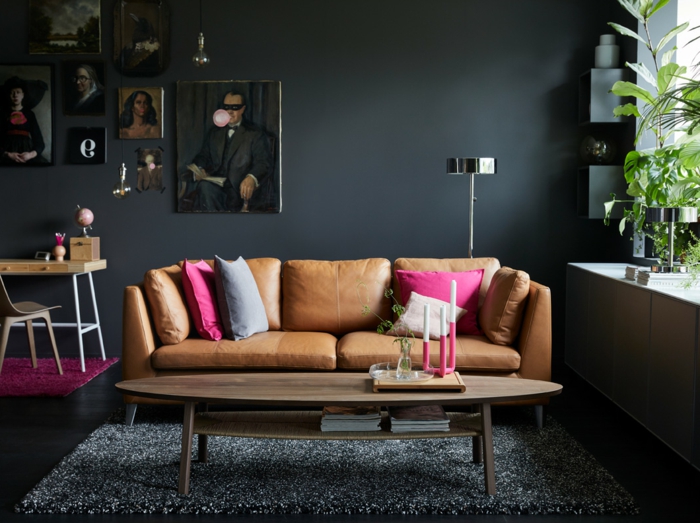 habitación gris, salón con sofá de cuero, cojines color ciclamen, paredes en gris pizarra oscuro, retratos al oleo, suelo laminado, tapete