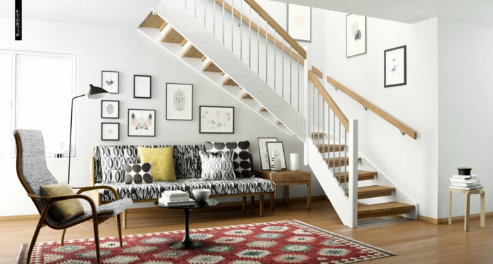 casa con escalera, cuadros en marcos negros, sofá con cojines en figuras geométricas, alfombra en rojo, sillón y mesita de café redonda