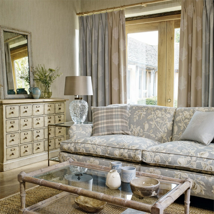 decoracion vintage salon, sofá con motivos florales, colores para habitaciones, ventana con cortinas, espejo, tapete de mimbre, mesa de bambu y vidrio